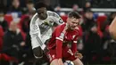 Pemain Liverpool, Conor Bradley (kiri) berebut bola dengan pemain Real Madrid, Vinicius Jr dalam laga Liga Champions 2025/2026 di Anfield, Liverpool, Inggris, Selasa (04/11/2025) waktu setempat. (AFP/Paul Ellis)