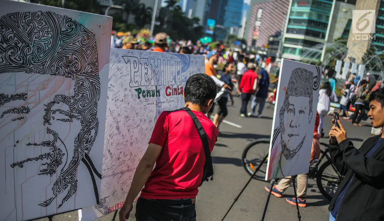Masyarakat menandatangani dilukisan capres 01 dan 02  yang bertema ‘ Pemilu Penuh Cinta’  saat Car Free day di kawasan Bundaran HI, Jakarta, MInggu (14/4). Kampanye tersebut untuk mengajak masyarakat untuk berpartisipasi dalam Pemilu secara Damai. (Liputan6.com/Faizal Fanani)
