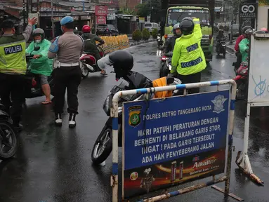 Petugas kepolisian melakukan penutupan jalan KH Hasyim Ashari, Kota Tangerang, Banten, Sabtu (16/7/2022). Akibat banjir yang merendam kawasan tersebut membuat petugas harus menutup jalur dan memutarbalikan para pengendara yang melintas. (Liputan6.com/Angga Yuniar)