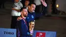 Kapten Argentina Lionel Messi (kiri) memegang Trofi Piala Dunia 2022 bersama pelatih Lionel Scaloni setibanya di Bandara Internasional Ezeiza di Ezeiza, provinsi Buenos Aires, Argentina (20/12/2022). Argentina mengakhiri penantian juara usai 36 tahun. (AFP/Luis Robayo)