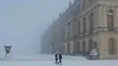Kondisi ini sangat berbahaya bagi pengendara maupun pejalan kaki di ibu kota Prancis tersebut. Tampak dalam foto, pejalan kaki berjalan melintasi taman Versailles yang tertutup salju, luar Kota Paris pada Selasa 6 Januari 2026. (GEOFFROY VAN DER HASSELT/AFP)