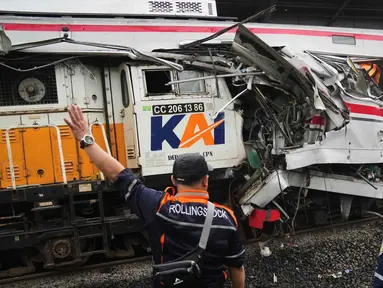 Para pekerja memeriksa kondisi lokomotif Kereta Api Jarak Jauh (KAJJ) Argo Bromo Anggrek dan salah satu gerbong Kereta Rel Listrik (KRL) Commuter Line yang mengalami kecelakaan di Stasiun Bekasi Timur, Bekasi, Jawa Barat, Selasa 28 April 2026. (AP Photo/Tatan Syuflana)