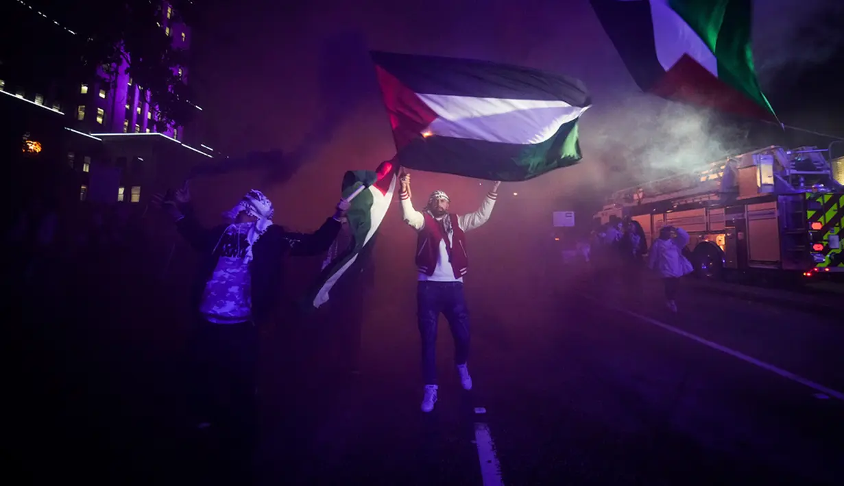 <p>Orang-orang mengibarkan bendera Palestina saat bom asap diledakkan dalam demonstrasi mendukung warga Palestina di Vancouver, British Columbia, Kanada, Kamis (19/10/2023). Unjuk rasa untuk mendukung warga Palestina dimulai di Balai Kota Vancouver dan berlanjut ke beberapa bagian kota. (Darryl Dyck/The Canadian Press via AP)</p>