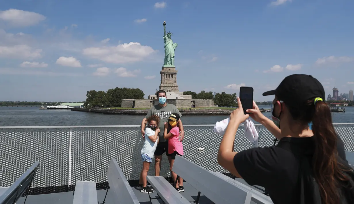 Sejumlah pengunjung berfoto dengan latar Patung Liberty di kapal pesiar yang menuju Pulau Liberty di New York, Amerika Serikat (AS) (20/7/2020). Pulau Liberty tempat Patung Liberty berada dibuka kembali pada Senin, meski bagian dalam area patung dan museum masih ditutup untuk umum. (Xinhua/Wang Ying