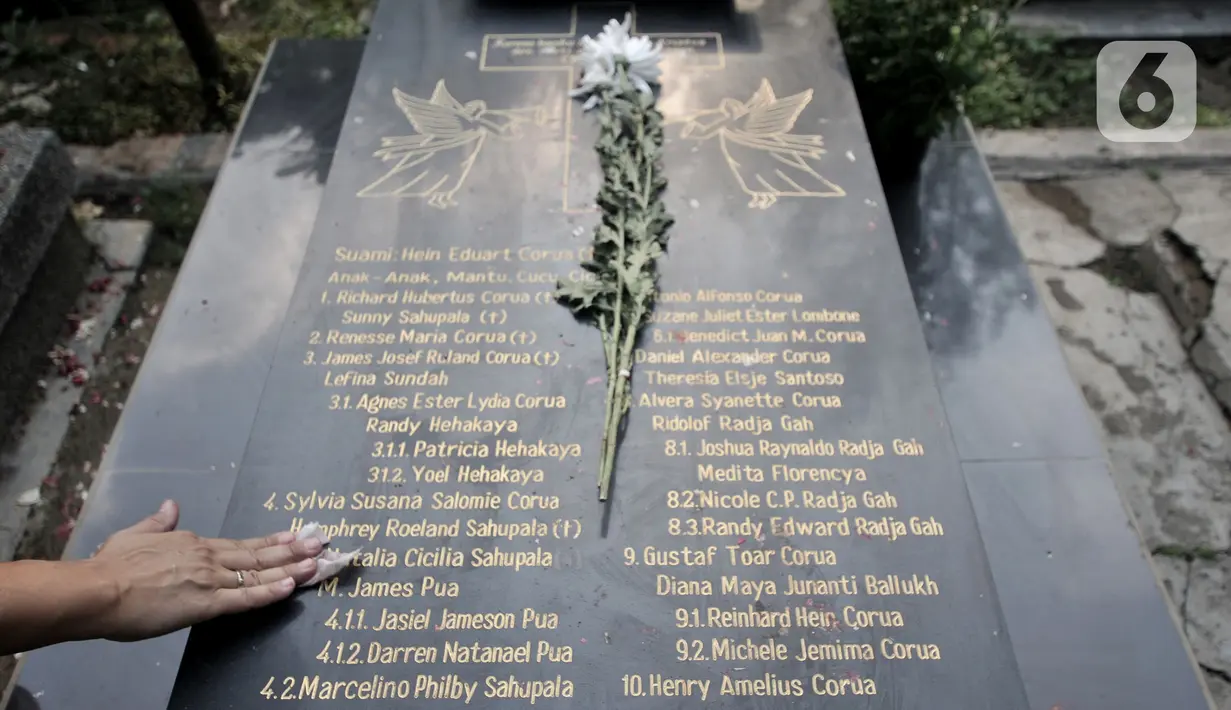 Keluarga membersihkan makam saat ziarah di kompleks pemakaman Gereja Tugu, Semper, Jakarta, Senin (23/12/2019). Ziarah menjadi tradisi keluarga keturunan Portugis di Kampung Tugu menjelang Hari Raya Natal. (merdeka.com/Iqbal Nugroho)