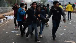 Sejumlah mahasiswa menggotong rekan mereka yang terluka saat demonstrasi menolak pengesahan RUU KUHP dan revisi UU KPK di depan Gedung DPR, Jakarta, Selasa (24/9/2019). Sejumlah mahasiswa tumbang setelah polisi menembakkan gas air mata untuk membubarkan demonstrasi. (ADEK BERRY/AFP)