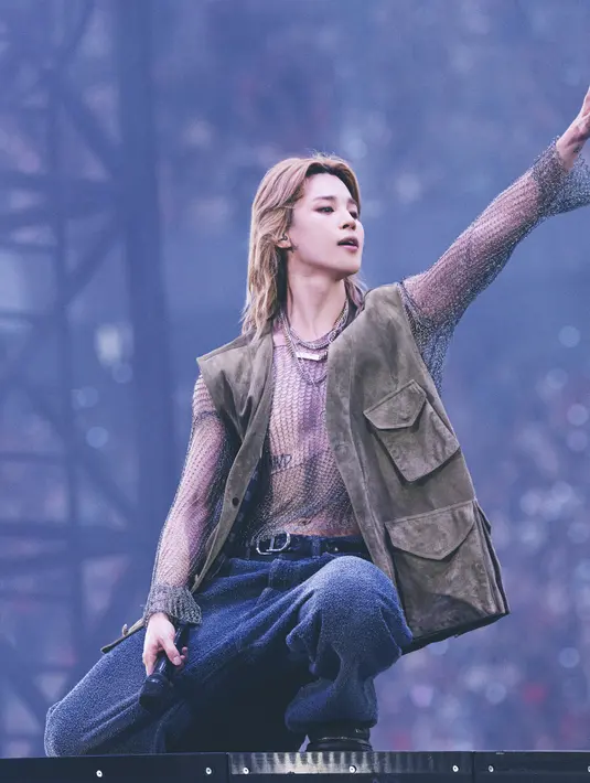 Jimin pamerkan postur tubuhnya dengan atasan rajut lurex perak berlapis vest berwarna khaki. Dipadu dengan celana panjang katun biru tua. Ia juga mengenakan ikat pinggang kulit hitam kepang dan sepasang sepatu kulit hitam. [Dior]