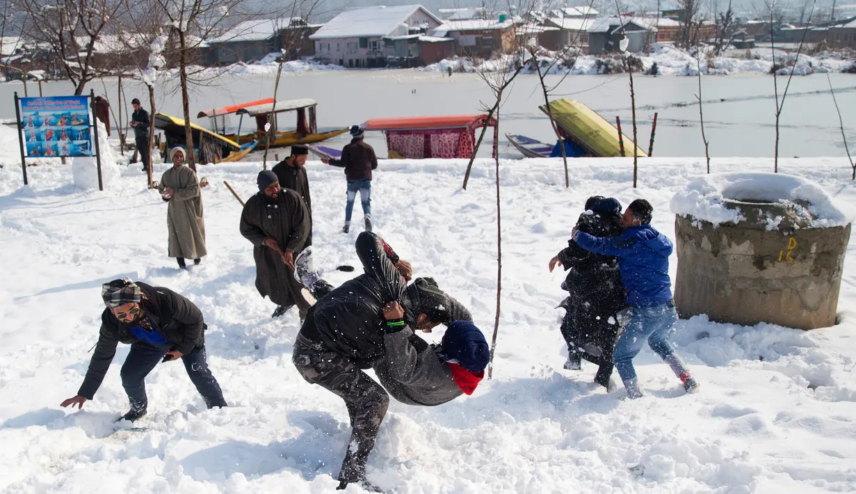 Sejumlah pria bermain di lapangan yang tertutup salju di Srinagar, kawasan Kashmir yang dikuasai India, Sabtu (5/1). Wilayah Kashmir mengalami salju selama beberapa hari yang mengakibatkan terputus jalan raya Jammu-Srinagar (AP Photo/Dar Yasin)