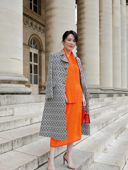 Yu Feihong terlihat mature dengan midi dress oranye dan long coat abu-abu [Fendi]