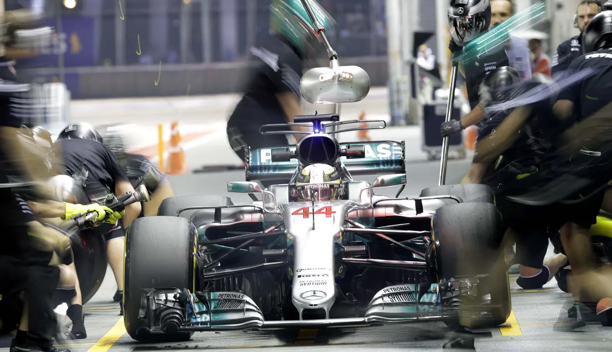 Pebalap Mercedes, Lewis Hamilton menanti perbaikan mobilnya oleh mekanik saat berada di pit lane pada sesi latihan bebas F1 GP Singapura, Marina Bay City Circuit, (15/9/2017). (AP/Wong Maye-E)