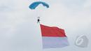 Aksi terjun payung prajurit TNI AU membawa bendera merah putih saat peringatan HUT ke-69 TNI AU Tahun 2015 di Lanud Halim Perdanakusuma, Jakarta, Kamis (9/4/2015). Acara tersebut menampilkan demo darat dan atraksi udara. (Liputan6.com/Herman Zakharia)