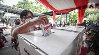 Petugas memasukkan surat suara saat simulasi Pemilu 2024 di Kantor KPU RI, Jakarta, Selasa (22/3/2022). Simulasi  digelar untuk memberikan edukasi kepada masyarakat terkait proses pemungutan dan penghitungan suara pemilu serentak yang akan dilaksanakan tahun 2024. (Liputan6.com/Faizal Fanani)