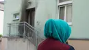Seorang wanita berhijab berdiri di pintu Masjid Fatih Camii yang rusak akibat serangan bom di Dresden, Jerman Timur, Senin (26/9) malam. Tidak ada korban namun terdapat kerusakan di bangunan masjid akibat getaran ledakan itu. (SEBASTIAN KAHNERT/DPA/AFP)