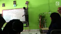 Siswa memasang pigura bergambar Wapres Jusuf Kalla di dalam kelas SMP Negeri 6 Palu, Sulawesi Tengah, Senin (8/10). Pascagempa dan tsunami Palu, siswa sekolah belum memulai aktivitas belajar mengajar. (Liputan6.com/Fery Pradolo)