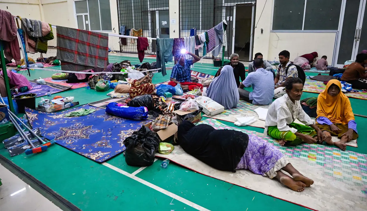 Pemkab juga membangun dapur umum, pos kesehatan dan distribusi logistik sejak dua hari terakhir. Tampak dalam foto, warga desa terdampak banjir beristirahat di tempat pengungsian setelah banjir bandang melanda Meureudu, Kabupaten Pidie Jaya, Provinsi Aceh, pada 29 November 2025. (CHAIDEER MAHYUDDIN/AFP)