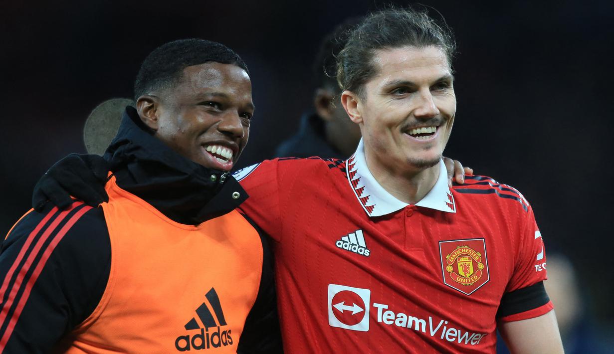 Pemain Manchester United, Marcel Sabitzer (kanan) dan Tyrell Malacia berjalan meninggalkan lapangan setelah laga pekan ke-22 Liga Inggris 2022/2023 melawan Crytal Palace di Old Trafford, Manchester, Sabtu (04/02/2023). MU berhasil menang dengan skor 2-1 melalui gol Bruno Fernandes dan Marcus Rashford. (AFP/Lindsey Parnaby)