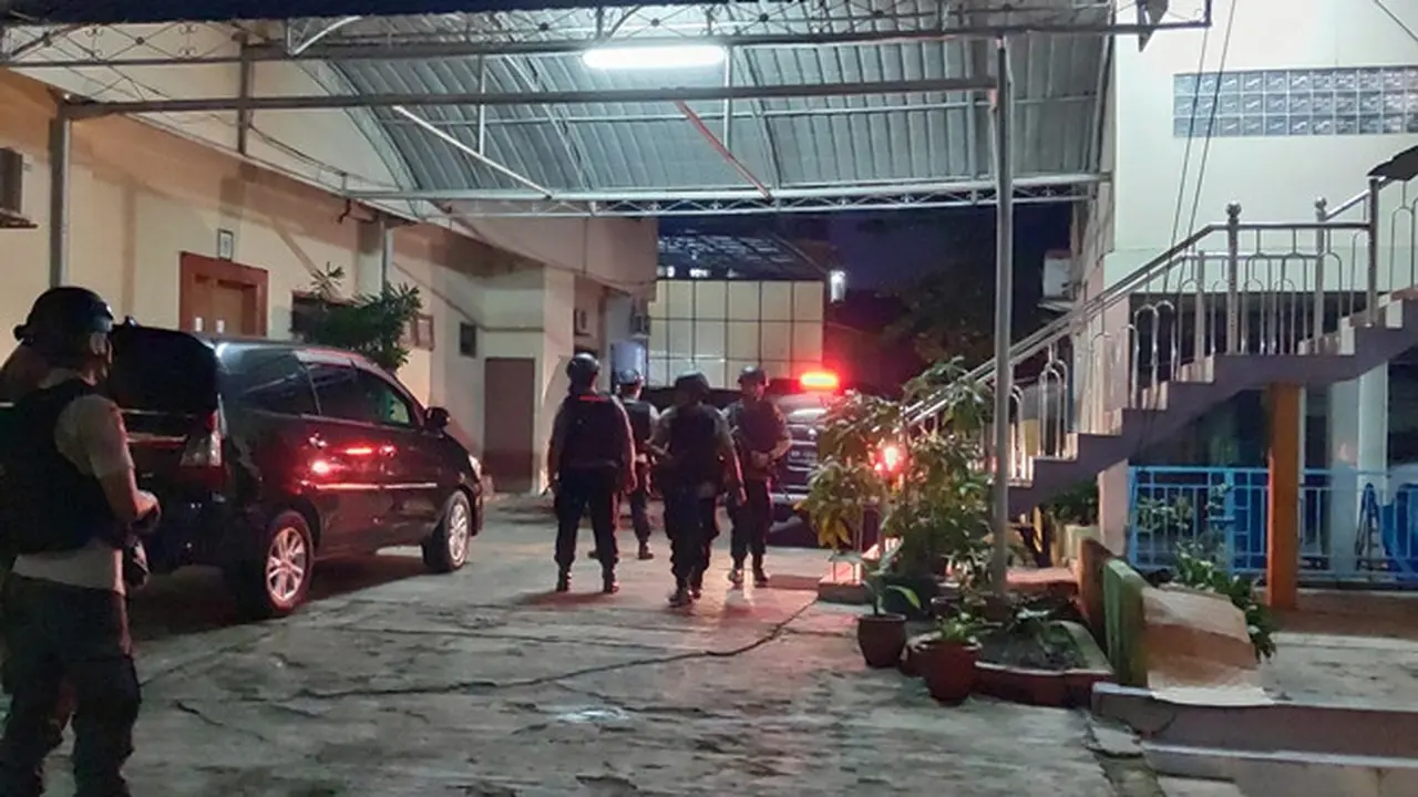 Polisi bersenjata lengkap mengawal penyidik KPK menggeledah rumah pengusaha terkait korupsi proyek jalan di Bengkalis.