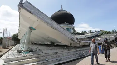 Warga melintas di depan masjid yang roboh usai gempa di Meuredu, Pidie Jaya, Aceh, Rabu (7/11). Selain meruntuhkan bangunan, gempa bumi berkuatan 6,4 SR ini telah menelan banyak korban jiwa. (Antara Foto / Irwansyah Putra / via REUTERS)