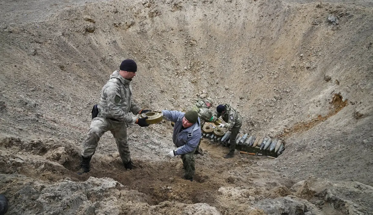 Pencari ranjau dari Kementerian Dalam Negeri Ukraina menyiapkan bahan peledak pada sebuah lubang untuk meledakkannya dekat ladang ranjau setelah pertempuran baru-baru ini di Desa Moshchun, dekat Kiev, Ukraina, 19 April 2022. (AP Photo/Efrem Lukatsky)