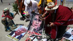 Dukun Peru melakukan ritual prediksi pada poster bergambar Capres AS dari Partai Demokrat, Hillary Clinton dan rivalnya dari Partai Republik, Donald Trump menjelang pemilihan presiden AS, di Lima, Peru, Senin (7/11). (REUTERS/Mariana Bazo)