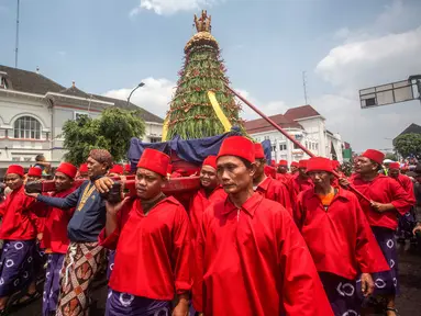 Para pengawal keraton yang dikenal secara lokal sebagai ‘abdi dalem’ membawa gunungan, sebuah persembahan berbentuk gunung dari hasil panen, selama upacara Grebeg, tradisi suci Keraton Yogyakarta pada 5 September 2025. (DEVI RAHMAN/AFP)
