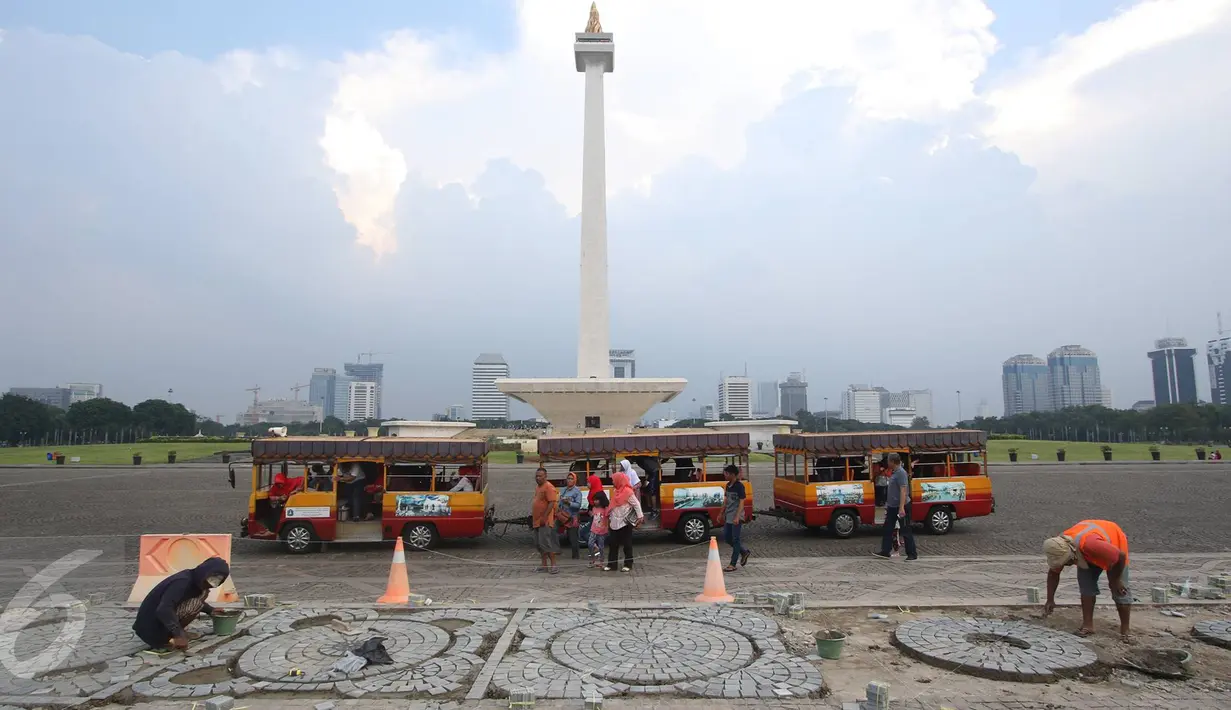 Para pekerja mengganti batu pelataran yang rusak di kawasan Monas, Jakarta, Kamis (10/11). Hal tersebut dilakukan untuk menjaga kawasan Monas agar tetap terawat dan nyaman bagi pengunjung. (Liputan6.com/Immanuel Antonius)