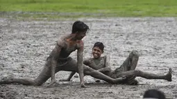 Anak-anak memainkan permainan Kabaddi di sebuah lahan yang digenangi air di Kolkata (8/9/2019).  Olahraga ini awalnya merupakan permainan untuk mempersiapkan tentara. (AFP Photo/Dibyangshu Sarkar)