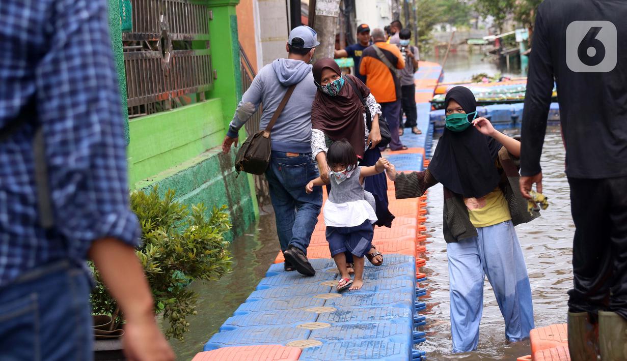Warga berjalan melintasi jembatan apung saat banjir melanda Perumahan Periuk Damai, Tangerang, Banten, Selasa (23/2/2021). Adanya jembatan apung mempermudah warga saat melintasi banjir setinggi 2,5 meter di tempat tersebut. (Liputan6.com/Angga Yuniar)