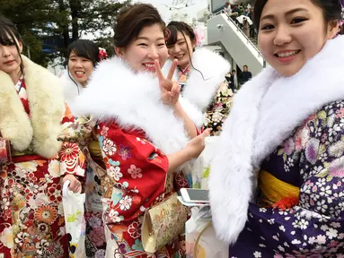 Sejumlah gadis di Jepang berkimono menuju salah satu taman hiburan di Tokyo, Jepang, Senin (9/1). Kehadiran mereka untuk merayakan Coming of Age Day atau Hari Datangnya Kedewasaan. (AFP Photo/ TORU YAMANAKA)