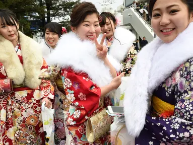 Sejumlah gadis di Jepang berkimono menuju salah satu taman hiburan di Tokyo, Jepang, Senin (9/1). Kehadiran mereka untuk merayakan Coming of Age Day atau Hari Datangnya Kedewasaan. (AFP Photo/ TORU YAMANAKA)