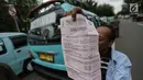 Seorang pengemudi angkutan menunjukkan surat tilang saat menggelar unjuk rasa di depan Balai Kota, Jakarta, Senin (22/1). Para sopir ini menuntut dibukanya jalan Jatibaru Raya dan putaran di depan Blok A Tanah Abang. (Liputan6.com/Faizal Fanani)