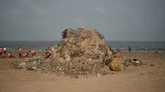 Petugas kebersihan berada di samping tumpukan sampah plastik terlihat di pantai Juhu di Mumbai, India (2/6). (AFP PHoto/Punit Paranjpe)
