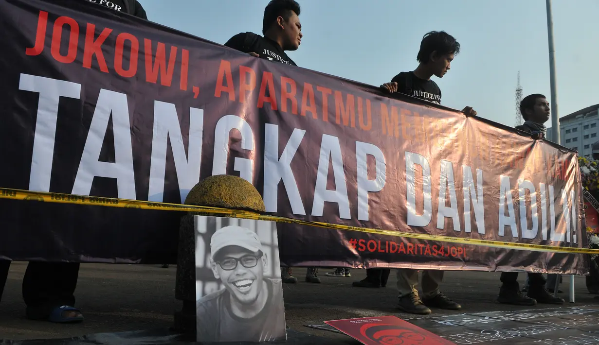 Spanduk berisi tuntutan penuntasan kasus pelanggaran HAM dibentangkan saat aksi kamisan di depan Istana Negara, Jakarta, Kamis (2/7/15). Dalam aksinya mereka meminta kepada Jokowi untuk menuntaskan kasus pembunuhan Jopi. (Liputan6.com/Herman Zakharia)