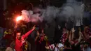 Warga Madrid menyalakan flare saat menyambut konvoi Atletico Madrid merayakan gelar Liga Europa di Madrid, Jumat (18/5/2018). Kota Madrid menjadi merah saat perayaan gelar juara Atletico. (AFP/Javier Soriano)