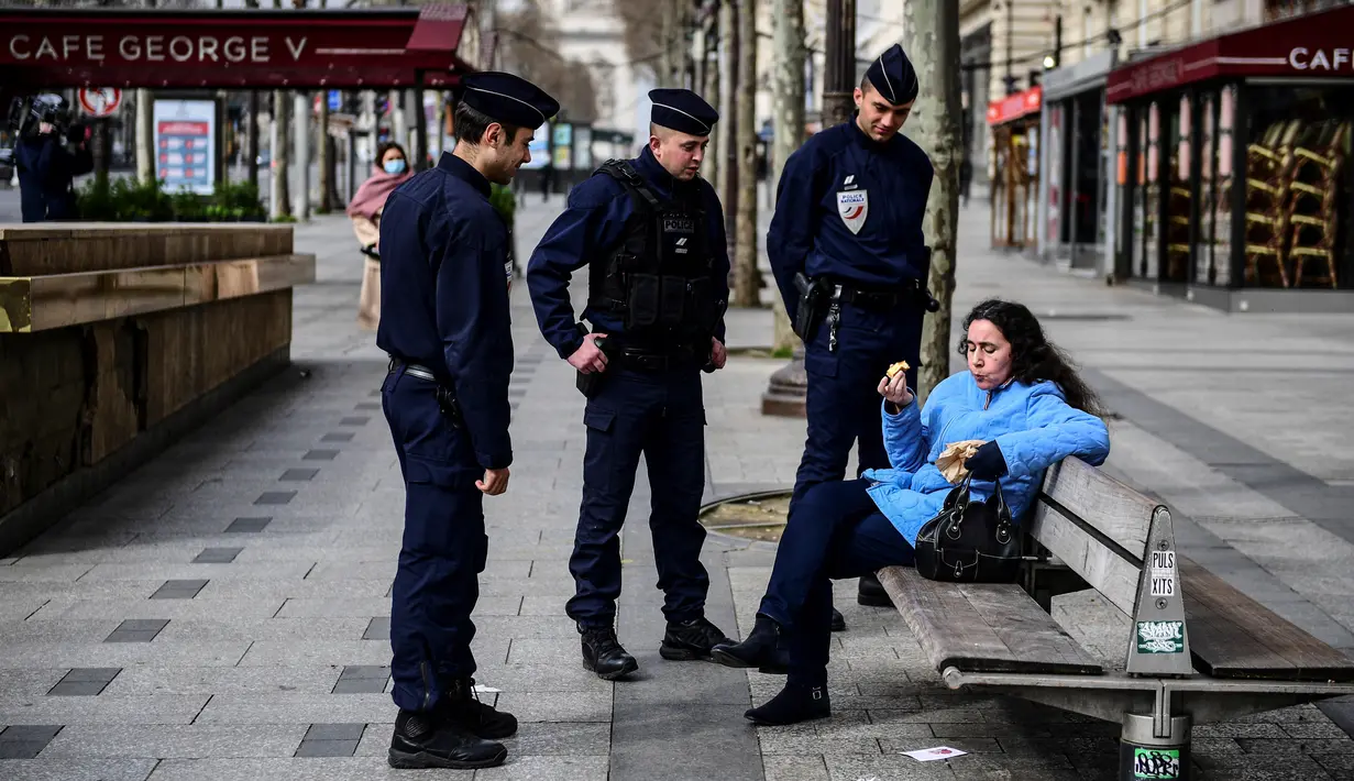 Polisi memeriksa seorang wanita saat lockdown di Jalan Champs-Elysees, Paris, Prancis, Selasa (17/3/2020). Polisi merazia warga yang masih berkeliaran di luar rumah saat Prancis memberlakukan lockdown akibat virus corona COVID-19. (MARTIN BUREAU/AFP)