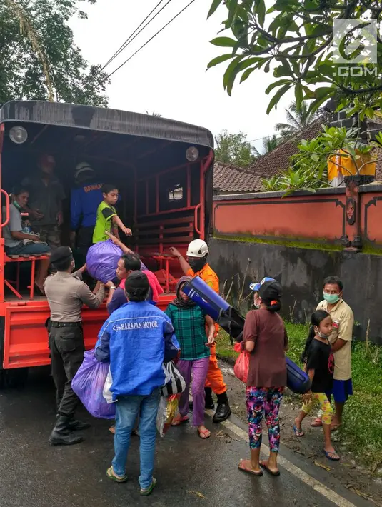 Petugas membantu warga menaiki truk akibat erupsi Gunung Agung di Desa Jungutan, Karangasem, Bali (28/11). Status Gunung Agung yang menjadi awas membuat warga mengungsi ke sejumlah titik penampungan. (Liputan6.com/Dewi Divianta)
