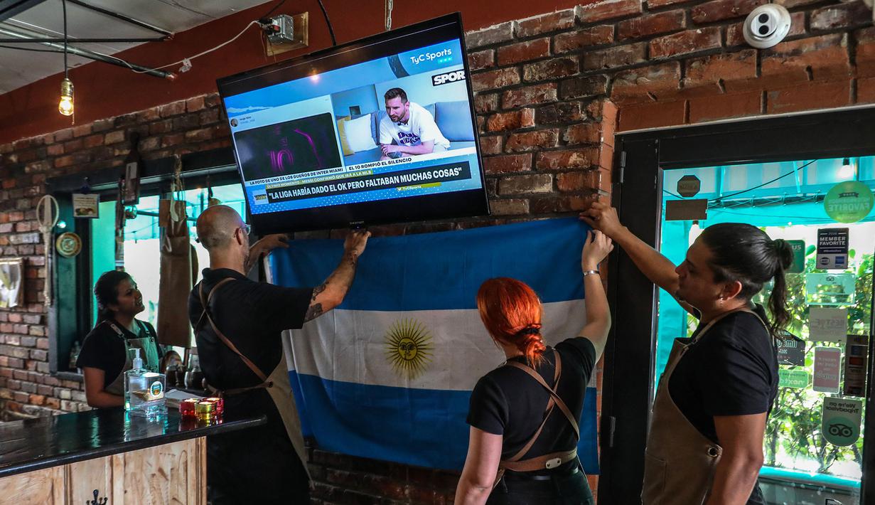 Sejumlah karyawan di restoran Argentina di Miami, Amerika Serikat melihat Lionel Messi yang sedang memberikan pernyataan di televisi. Messi memutuskan untuk bergabung dengan klub MLS, Inter Miami, pada Rabu (7/6/2023). (AFP/Giorgio Viera)