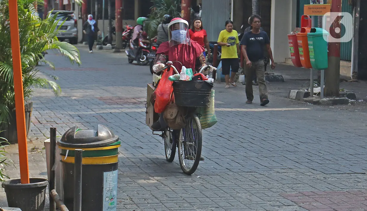 Tidar (46), mengayuh saat berjualan jamu di Pasar Baru, Jakarta, Kamis (11/06/2020). Penjual jamu tradisional keliling ini tampak mematuhi protokol kesehatan pencegahan COVID-19 dengan mengenakan masker, face shield, dan sarung tangan dalam melayani pelanggan setianya. (Liputan6.com/Herman Zakharia)