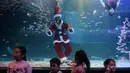 Penyelam berpakaian Sinterklas menyapa anak-anak saat tampil dalam pertunjukan bawah laut bertema Natal di Akuarium COEX, Seoul, Korea Selatan, Jumat (7/12). (Ed JONES/AFP)