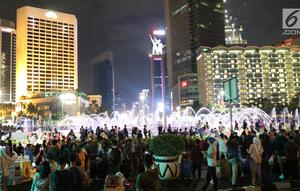 Warga menikmati car free night saat malam pergantian tahun di kawasan Bundaran HI, Jakarta, Senin (31/12). Hujan yang mengguyur Jakarta sejak siang tidak menyurutkan antusias warga menikmati&nbsp;car free night. (Liputan6.com/Angga Yuniar)