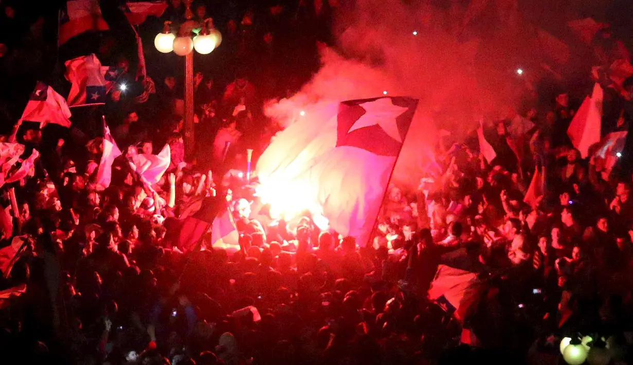Suporter Chili berkumpul di jalan menyalakan suar merayakan kemenangan Chili atas Peru di Copa Amerika 2015 di kota Santiago, (29/6/2015). Chile melaju ke final usai mengalahkan Peru 2-1 berkat dua gol Eduardo Vargas. (REUTERS/Catherine Allen)