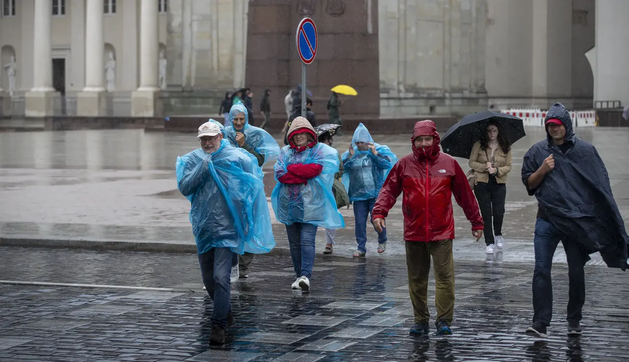 Orang-orang menyeberang jalan saat hari hujan, di Vilnius, Lituania, Senin (29/7/2024). (AP Photo/Mindaugas Kulbis)