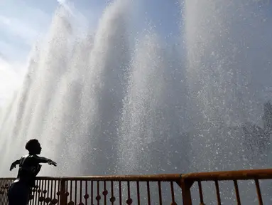 Seorang wanita membentangkan tangannya di dekat mancur di Taman Battersea, London, Inggris, Selasa (13/9). Taman Battersea menjadi tempat favorit warga saat cuaca panas melanda Inggris. (REUTERS / Stefan Wermuth)