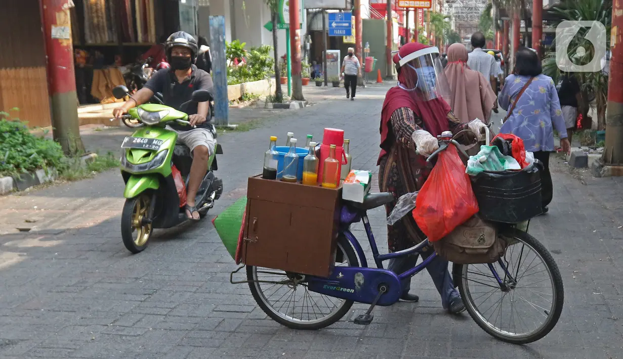 Tidar (46), mengayuh saat berjualan jamu di Pasar Baru, Jakarta, Kamis (11/06/2020). Penjual jamu tradisional keliling ini tampak mematuhi protokol kesehatan pencegahan COVID-19 dengan mengenakan masker, face shield, dan sarung tangan dalam melayani pelanggan setianya. (Liputan6.com/Herman Zakharia)