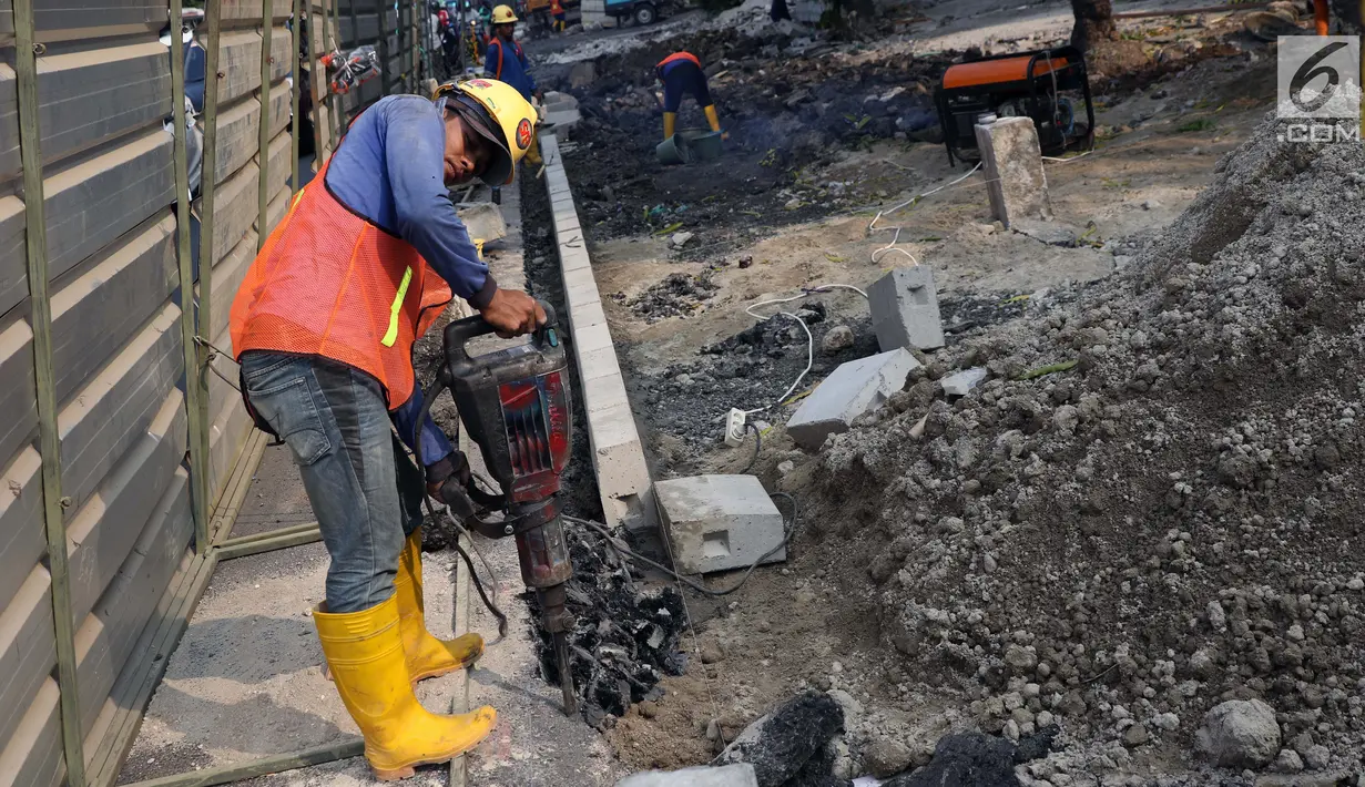 Aktivitas pekerja menyelesaikan proyek revitalisasi trotoar di Jalan Salemba Raya, Jakarta, Jumat (6/9/2019). Proyek revitalisasi trotoar dengan anggaran Rp 75 miliar ini ditargetkan rampung pada Desember mendatang. (Liputan6.com/Helmi Fithriansyah)