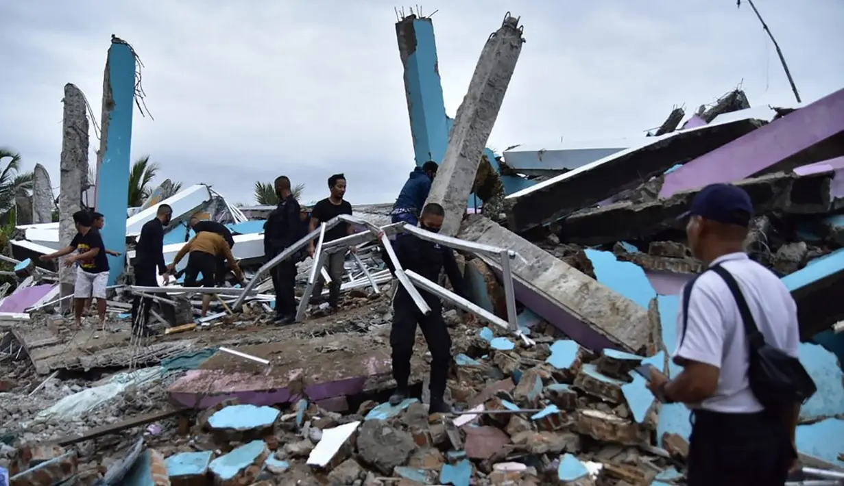 Tim penyelamat membuang puing-puing saat mencari korban dari Rumah Sakit Mitra Manakarra yang runtuh akibat gempa, Kota Mamuju, Sulawesi Barat, Indonesia, Jumat (15/1/2021). Sebanyak 20 pasien dan staf terjebak di bawah reruntuhan bangunan. (Firdaus/AFP)