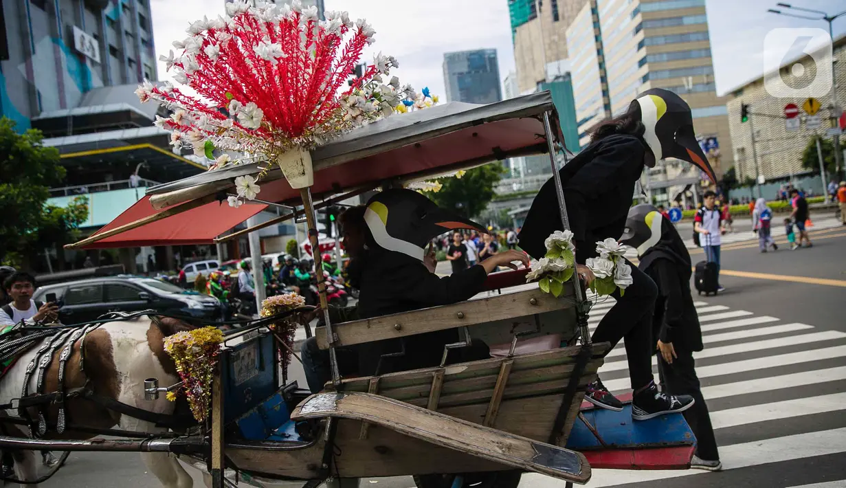 Aktivis Greenpeace turun dari kereta kuda mengenakan topeng penguin saat menggelar aksi dalam car free day di kawasan Thamrin, Jakarta, Minggu (9/2/2020). Mereka mengajak pemerintah untuk berpartisipasi dalam mewujudkan Perjanjian Laut Internasional (Global Ocean Treaty). (Liputan6.com/FaizalFanani)
