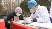 Dokter menangani warga setempat di sebuah rumah sakit keliling di Distrik Chang'an, Provinsi Hebei, 12 Maret 2020. Sebuah rumah sakit pengobatan tradisional China keliling menyediakan layanan kesehatan bagi penduduk setempat di tengah perang melawan virus corona COVID-19. (Xinhua/Liang Zidong)