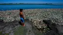 Seorang anak laki-laki bernama Angel menyaksikan ikan mati menumpuk di tepi Sungai Salado tempat dia pergi bersama ayahnya untuk memancing di Provinsi Buenos Aires, Argentina, 22 Januari 2023. (AP Photo/Natacha Pisarenko)