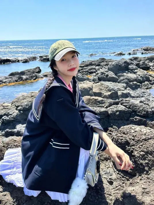 Joy Red Velvet tampil mengenakan outer warna hitam dipadukan rok ruffle putih, sambil membawa handbag Chanel Nya. Topi cap hijau pun digunakan di atas rambut kepang duanya. [@_imyour_joy]